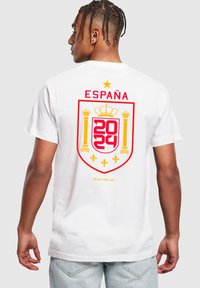 Hvid bomulds t-shirt med et stort rød og gul skjold design på ryggen med "ESPAÑA" og årene "2024" og "2022."
