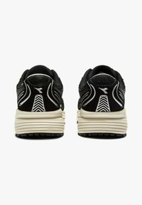 Baskets de sport noires avec un dessus texturé, des accents blancs prononcés et une semelle épaisse de couleur crème avec un motif de relief.