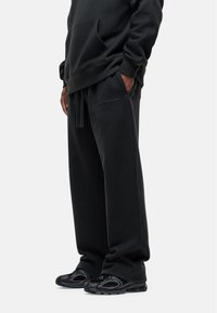 Zwarte sweatshirt en bijpassende sweatpants van zachte stof met een ontspannen pasvorm. De broek heeft een elastische tailleband en zijzakken.