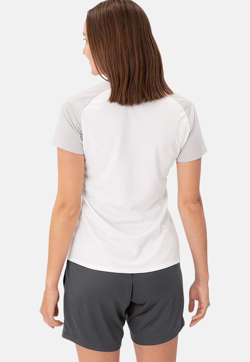 Maglietta sportiva a maniche corte di colore bianco con dettagli grigi, realizzata in tessuto traspirante. Abbinata a pantaloni corti grigi scuri per un look sportivo.