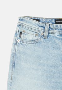 Ανοιχτού γαλάζιου χρώματος τζιν με ίσια κοπή. Διαθέτουν παραδοσιακό σχέδιο με πέντε τσέπες, μεταλλικά κουμπώματα και ετικέτα με το λογότυπο στη μέση.