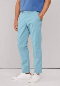 Pantalones de color azul claro con una textura suave, diseño de pierna recta, con trabillas para el cinturón, bolsillos frontales y cierre con botón. Combinados con zapatillas blancas.