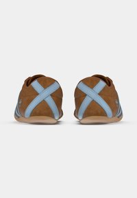 Καφέ δερμάτινα παπούτσια με μπλε λεπτομέρειες, που διαθέτουν σταυρωτό σχέδιο στο πίσω μέρος και ραφές. Χαμηλού προφίλ, στρογγυλεμένο σχήμα.