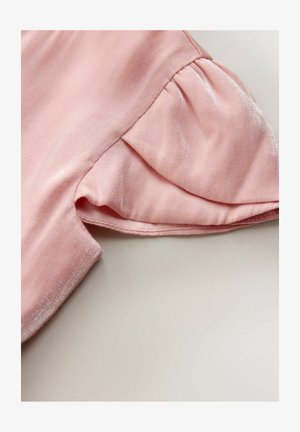 Țesătură roz deschis cu o textură netedă, având un detaliu de mânecă scurtă adunată și cusături ordonate de-a lungul marginilor.