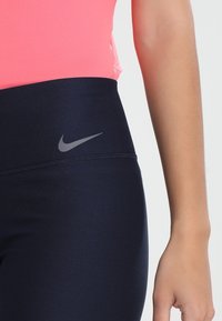 Marina leggings med hög midja, med en diskret grå Nike-logotyp och smidig, stretchig tyg för komfort och rörlighet.