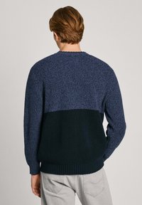 Stickad tröja med en tvåfärgad design, med en texturerad överdel i mörkblått och en slät mörkgrön botten. Rivet fåll och muddar.