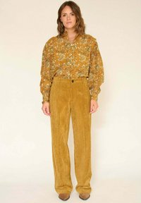 Blouse à manches longues à imprimé cachemire jaune avec une coupe décontractée, associée à un pantalon en velours côtelé moutarde côtelé taille haute.