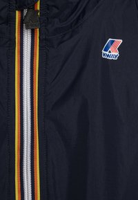 Giacca K-WAY blu con zip centrale e strisce multicolori: giallo, rosso e blu scuro. Include logo K-WAY sul petto.
