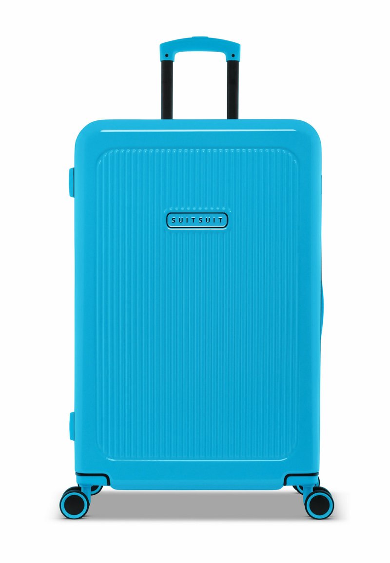 Lichtblauwe harde koffer met verticale ribbeltextuur, een uitschuifbare handgreep en vier multi-directionele wielen. Merkenlogo zichtbaar.