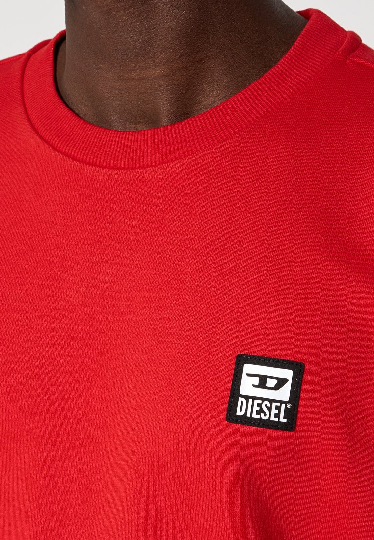 Felpa rossa in cotone con colletto a girocollo a coste e un'etichetta quadrata nera con il logo "DIESEL" sul petto.
