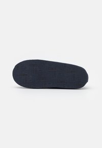 Suela de zapato de goma de color azul marino con un patrón de agarre texturizado, que presenta el nombre de la marca y la fecha de establecimiento en relieve, un borde curvado y un diseño robusto.