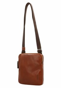 Braune Leder-Crossbody-Tasche mit glatter Textur, Reißverschluss und verstellbarem braunem Stoffgurt. Enthält eine Seitentasche und ein Logodetail.