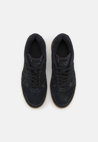 Černé semišové tenisky s vysokým střihem, vybavené černými tkaničkami, texturovanými detaily a hnědou gumovou podrážkou.