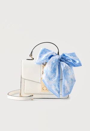 Hvid læderhåndtaske med guldlås og håndtag, dekoreret med et stort blå-hvidt mønstret silketørklæde bundet i en sløjfe.