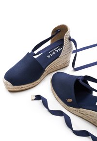 Zeppe espadrilles in tela blu navy con tacco intrecciato, suola in corda di juta e lacci al polso in nastro. Marchio distintivo ben visibile sulla soletta.