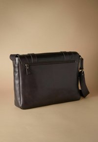 Dark brown leather messenger bag with a flat design, featuring a zippered front pocket, adjustable strap, and subtle stitching details.