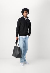 Black zip-up sweatshirt, light blue jeans, white sneakers, and a black leather tote bag. Simple design, casual fit, no patterns visible.