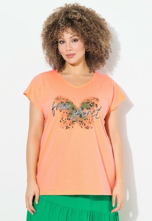 T-shirt corail à manches courtes avec un col en V, présentant un motif de papillon en imprimé léopard et le texte "free spirit" en noir.