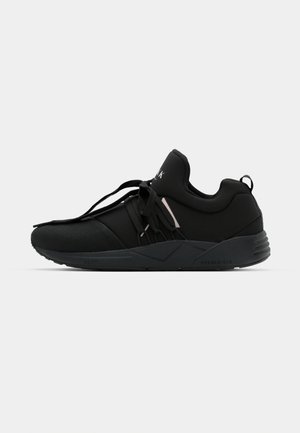 Schwarze Sport Schuhe mit einem Obermaterial aus Netzstoff und Synthetik, das ein elegantes Design aufweist, gepolsterten Schuhkragen und strukturierten Sohle. Akzentuiert mit subtilen Hardware-Elementen.