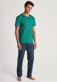 Groene katoenen T-shirt met ronde hals, gecombineerd met marineblauwe pyjamabroeken met een contrasterend lichtblauw autobezet. Casual ontwerp met een zachte textuur.