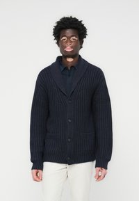 Morska pletena kardigan s reverima, zatvaranjem na gumb i dva prednja džepa. Ima teksturiranu tkaninu i rebraste manžete.