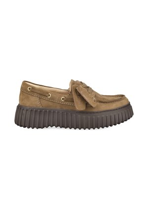 Brauner Veloursleder-Slipper mit dicker schwarzer profillierter Sohle und Lederband, das oben zu einer Schleife gebunden ist, Seitenansicht auf weißem Hintergrund.