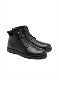 Czarne skórzane botki do kostki z teksturowaną powierzchnią, sznurowanym zapięciem i kontrastowym, miękkim wykończeniem. Posiadają solidną gumową podeszwę i szczegóły szewne.