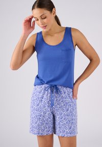 Blauwe katoenen top zonder mouwen met geschulpte randen en een zak, gecombineerd met lichtblauwe shorts met een patronen van bladeren en een koord in de taille.
