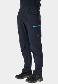 Granatowe spodnie softshell z elastycznym pasem, dwoma kieszeniami na zamek w kontrastującym niebieskim kolorze, zwężanym krojem i wzmocnionymi przeszyciami dla większej trwałości.