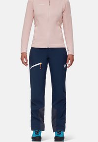 Kurtka polarowa w jasnoróżowym kolorze, z pełnym zamkiem, z długimi rękawami. Ciemnoniebieskie spodnie narciarskie z białymi akcentami zamka i szarymi siateczkowymi detalami przy kostkach.