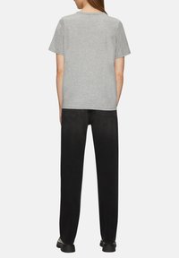 Grijze katoenen t-shirt met korte mouwen, een ronde hals, gecombineerd met zwarte rechte broek en zwarte schoenen, wat een casual outfit laat zien.