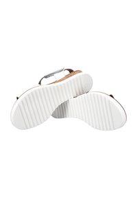 Sandalias blancas con una suela texturizada, plantilla de corcho y correa ajustable con hebilla. La parte superior es suave y elegante, complementando el diseño minimalista.