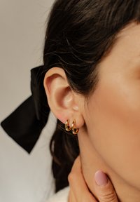 Boucles d'oreilles en or avec une finition lisse et polie. Deux petites anneaux fixés à l'oreille, mettant en valeur un design épuré et minimaliste.