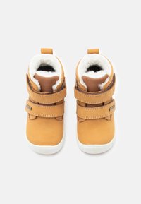 Botine din piele maro deschis cu căptușeală din blană sintetică, cu două benzi velcro pentru închidere și talpă din cauciuc alb. Design scurt, cu vârf rotunjit.