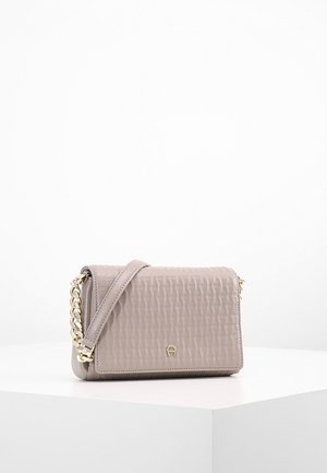 Sac bandoulière en cuir beige texturé avec chaîne dorée et sangle en cuir, forme rectangulaire, petit logo doré sur le rabat avant.