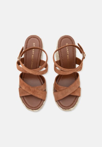 Sandales compensées en daim marron avec brides croisées à la cheville et aux orteils, fermeture à boucle et semelles tissées style espadrilles.