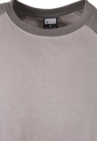 Ljusgrå sweatshirt med rundad halsringning och mörkgrå krage samt axlar, med en storlek medium etikett från "Urban Classics".