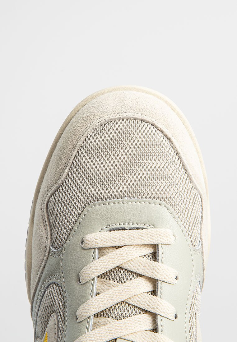 Jasnoszare sneakersy z teksturowaną siateczkową cholewką, beżowymi zamszowymi akcentami i białymi sznurówkami. Posiadają gumową podeszwę z delikatnym bieżnikiem.