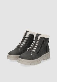 Bottes d'hiver noires avec doublure en fausse fourrure blanche, semelles épaisses beige, fermetures éclair latérales et lacets noirs sur fond gris.