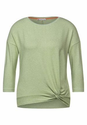 Hellgrünes Langarmshirt mit rundem Ausschnitt und einem gedrehten Knotendetail an der unteren rechten Seite.