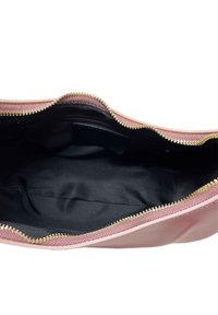 Interno di una borsa rosa con fodera nera; caratterizzata da una cerniera dorata lungo il bordo superiore, texture liscia con dettagli di cucitura minimi.