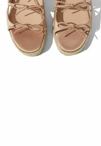 Roze espadrile sandale s satenskim trakama i mašnama. Okrogli vrh, pletena jute potplata, glatka tekstura na gornjoj površini.