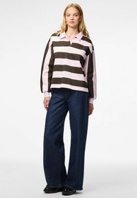 Pull-over à rayures horizontales roses et marron foncé, avec un col. Associé à un jean en denim foncé à jambes larges.