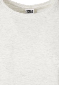 Gros plan sur un t-shirt gris clair à col rond avec une petite étiquette blanche à l'intérieur du col portant l'inscription « Urban Classics » en lettres noires.