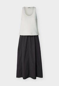 Άσπρο αμάνικο τοπ με λαιμόκοψη scoop, συνδυασμένο με μαύρη μακριά φούστα με ψηλή μέση και ελαφριές πιέτες.