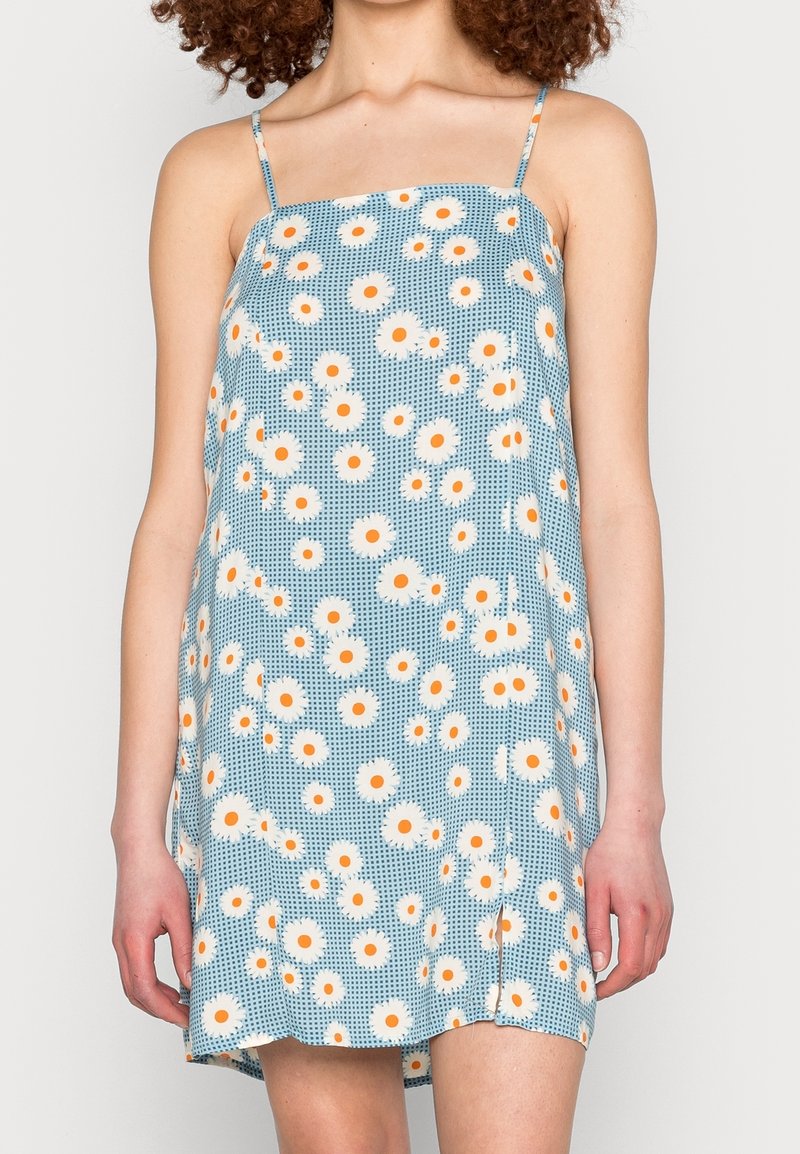 Bloemenjurk met dunne bandjes, voorzien van een blauwe achtergrond, witte en oranje madeliefjes, en een losse pasvorm; lichtgewicht stof met een textuurpatroon.