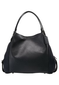 Czarna skórzana torebka o ziarnistej fakturze, zaokrąglonym kształcie, z dwoma uchwytami i małą przywieszką. Posiada granatowe boczne akcenty.