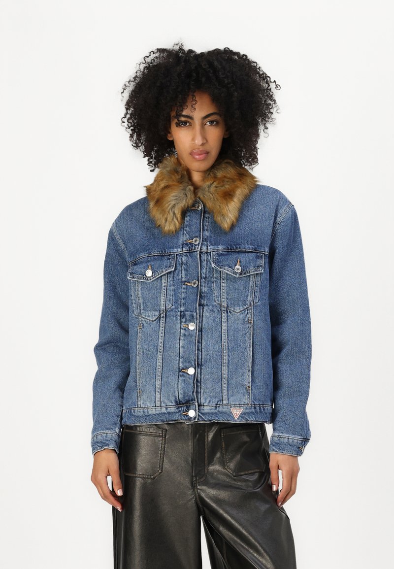 Denim jacket with a faux fur collar, blue color, button closure, two chest pockets, and a triangular logo on the hem. Textured fabric.