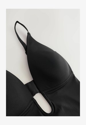 Soutien-gorge noir avec bonnets rembourrés, bretelles ajustables, texture lisse et un détail découpé au centre. Fabriqué en tissu élastique.