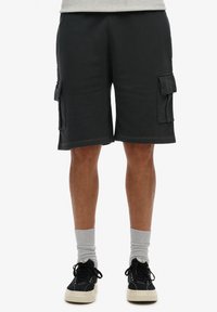 Pantalones cortos de cargo negros con dos bolsillos laterales, textura acanalada y un ajuste holgado. El dobladillo está ligeramente deshilachado para un aspecto relajado.